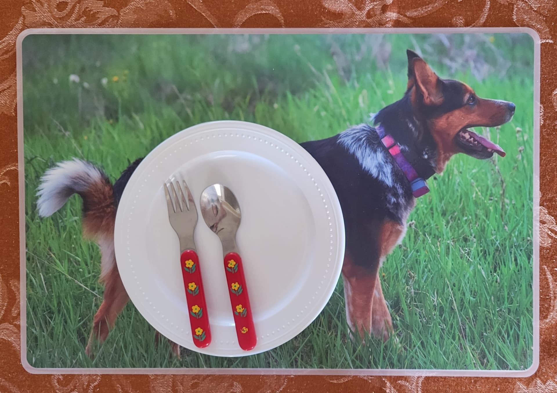 A picture of a dog on a plate with a fork and knife